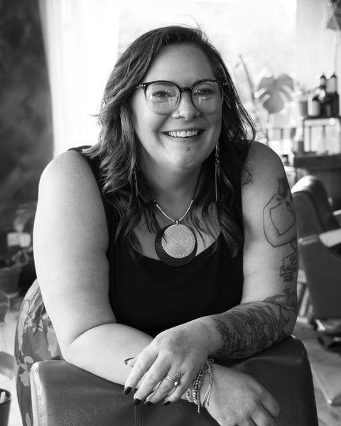 Black and white photo of a woman called Jen with tattoos sitting on a chair.